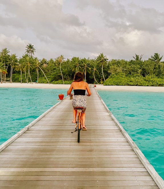 Cycling on a boardwalk over turquoise waters in the Maldives, an iconic luxury travel destination for international travelers seeking tropical paradise and relaxation